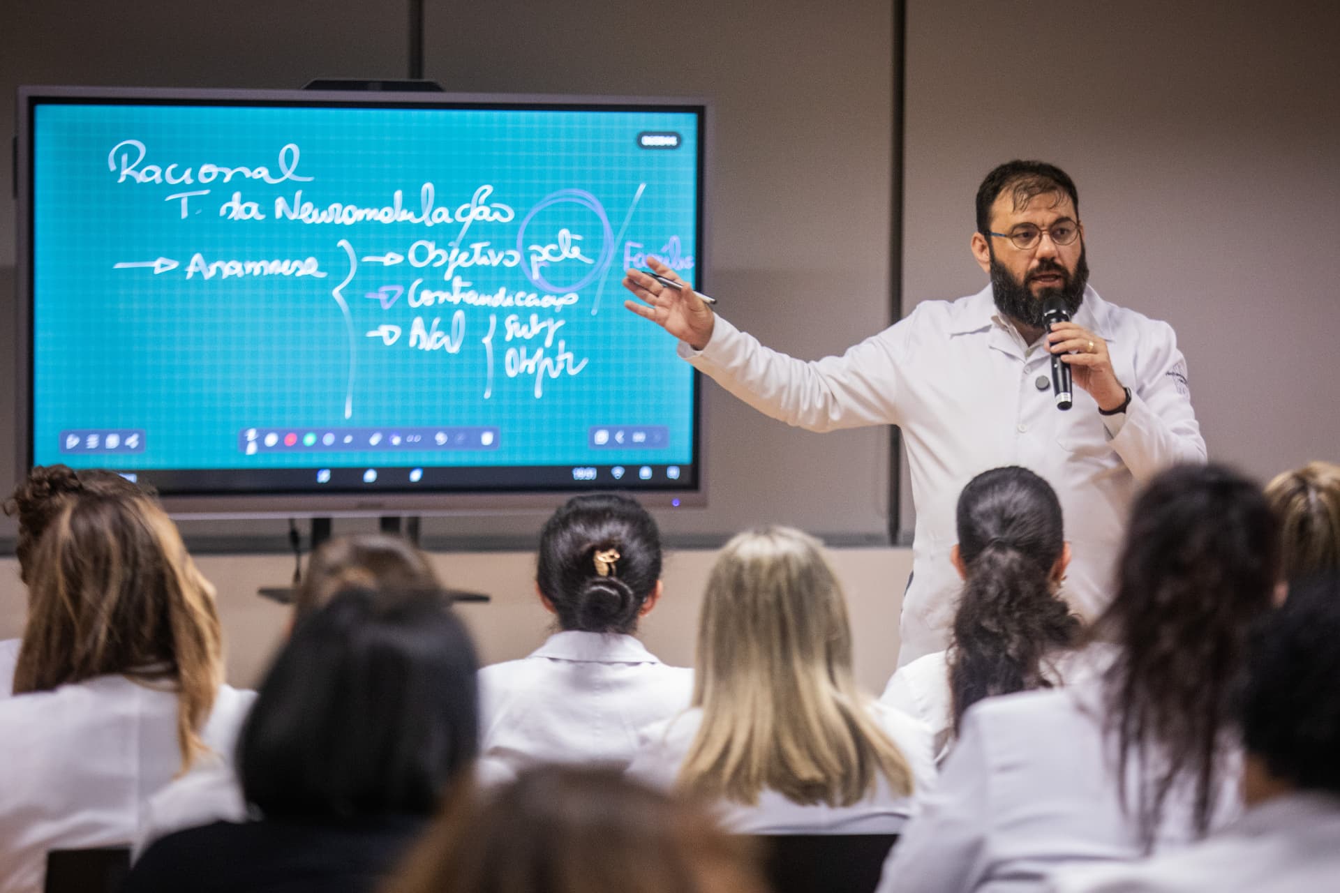 Prof. Dr. Ricardo Galhardoni explicando conteúdo de neuromodulação em aula para turma de profissionais da saúde
